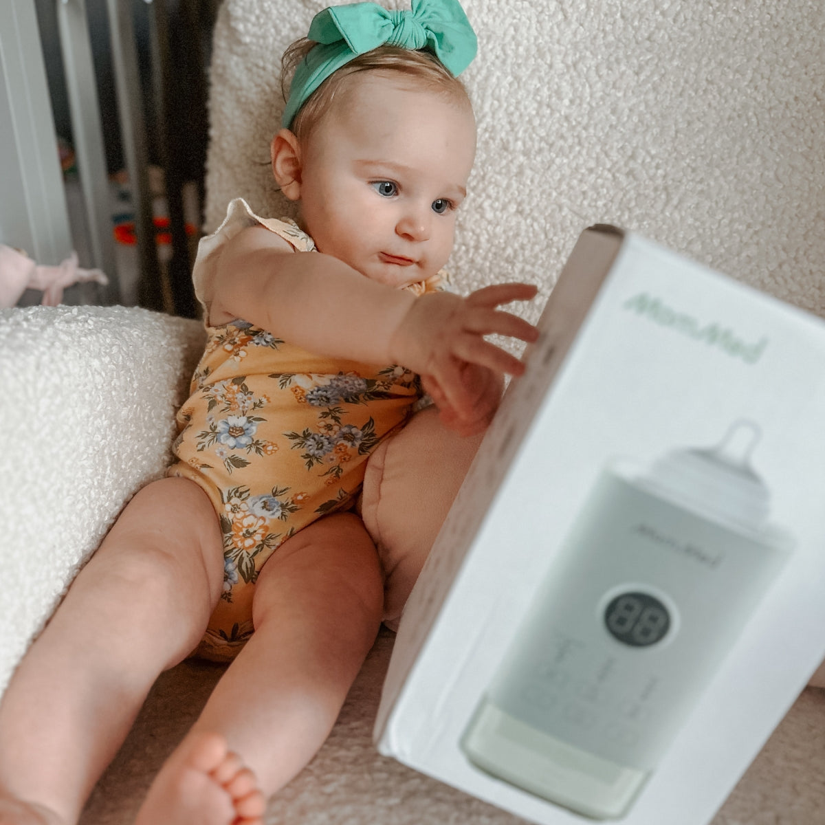 Baby happy and holding MomMed baby bottle warmer