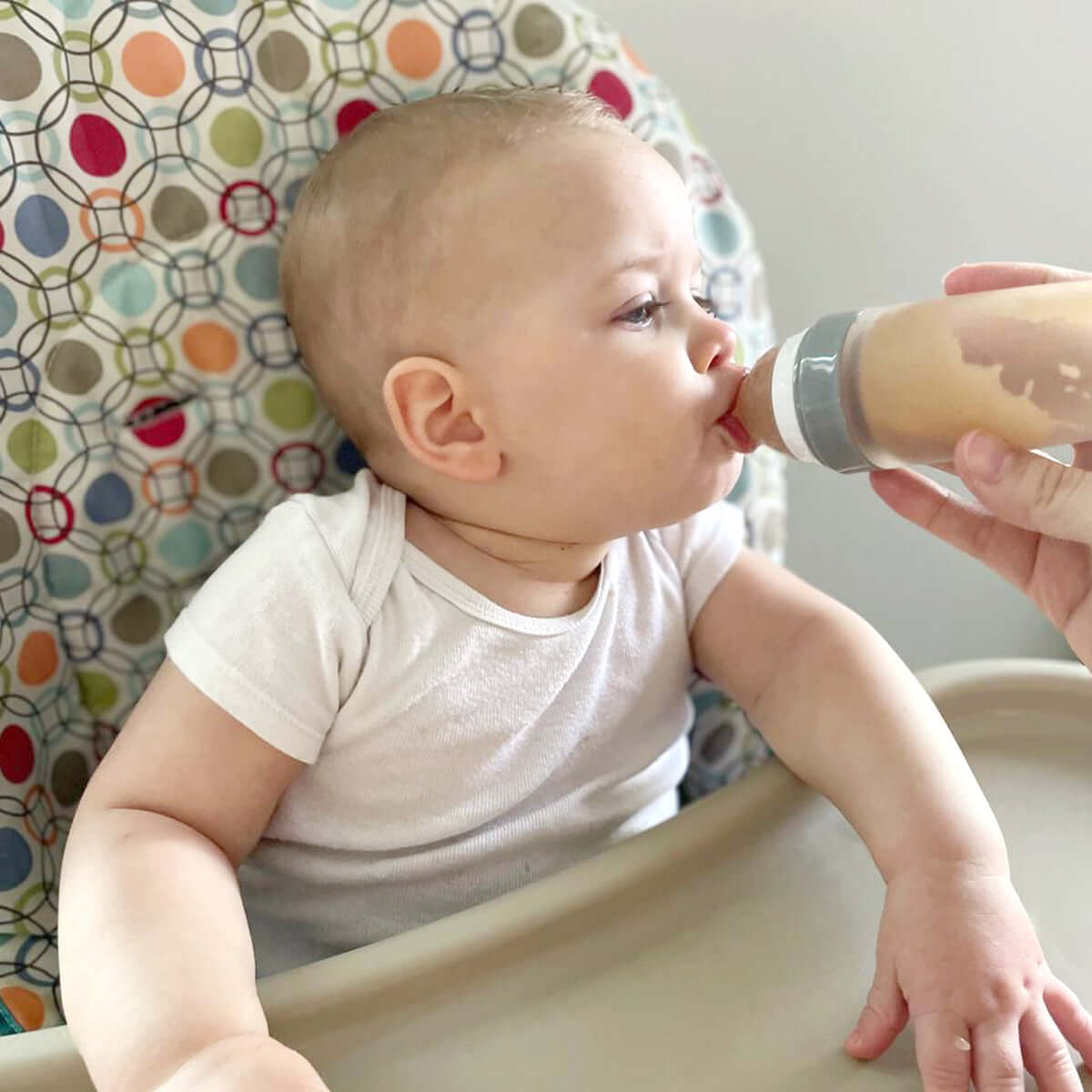 A mother is feeding her baby with MomMed Baby Spoon Bottle Feeder.