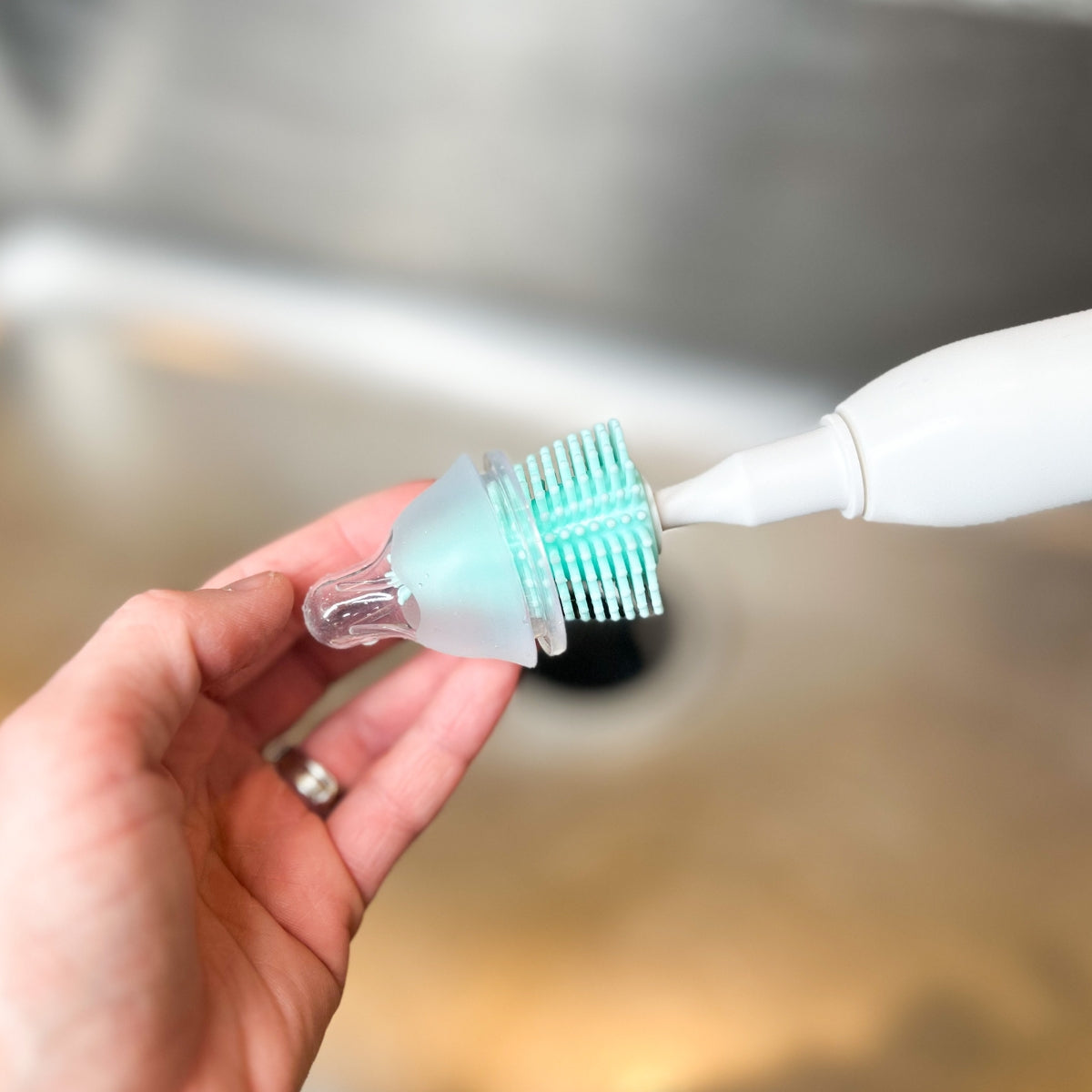 A mother uses the MomMed bottle brush on the bottle spout
