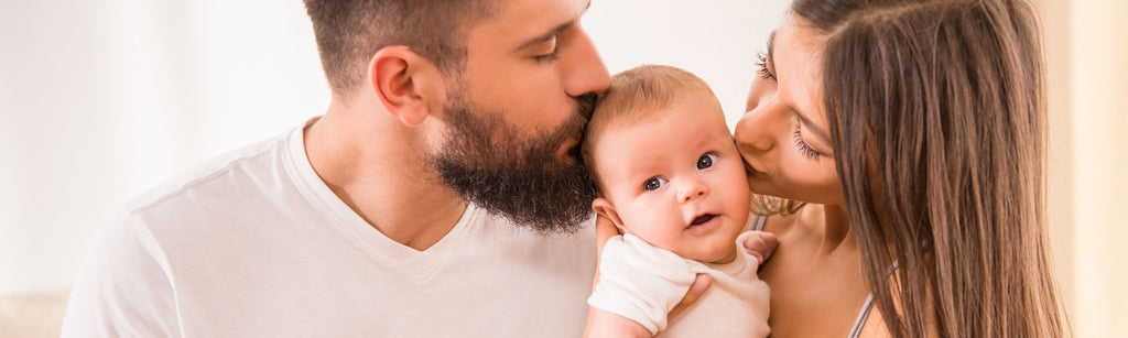 Parents kissing baby